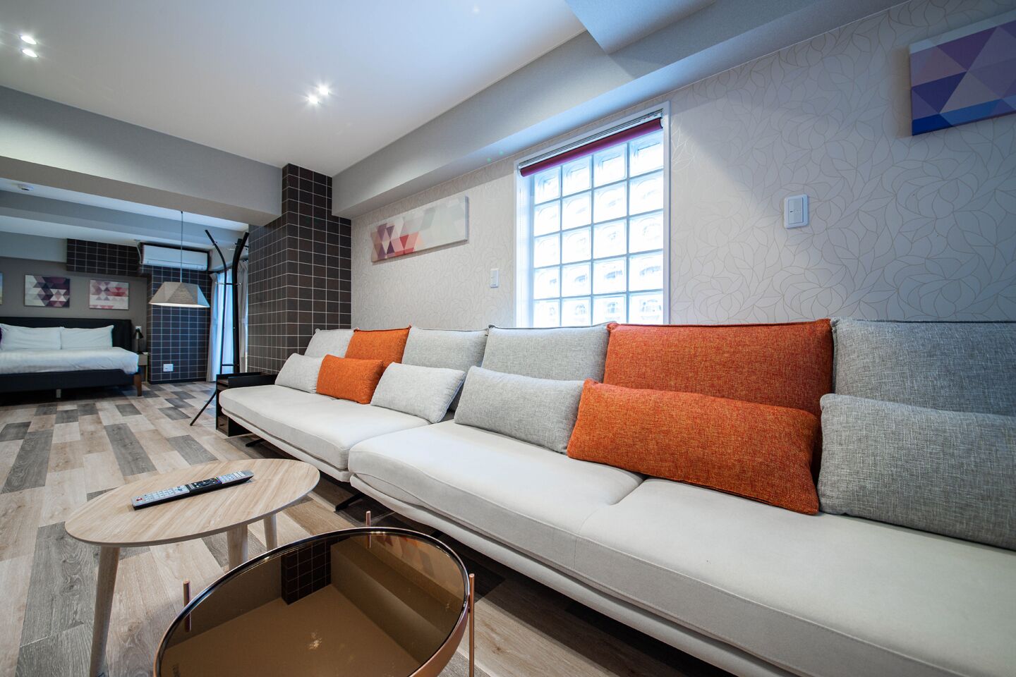 A modern living room with a sofa, a coffee table, and a bed in the background.