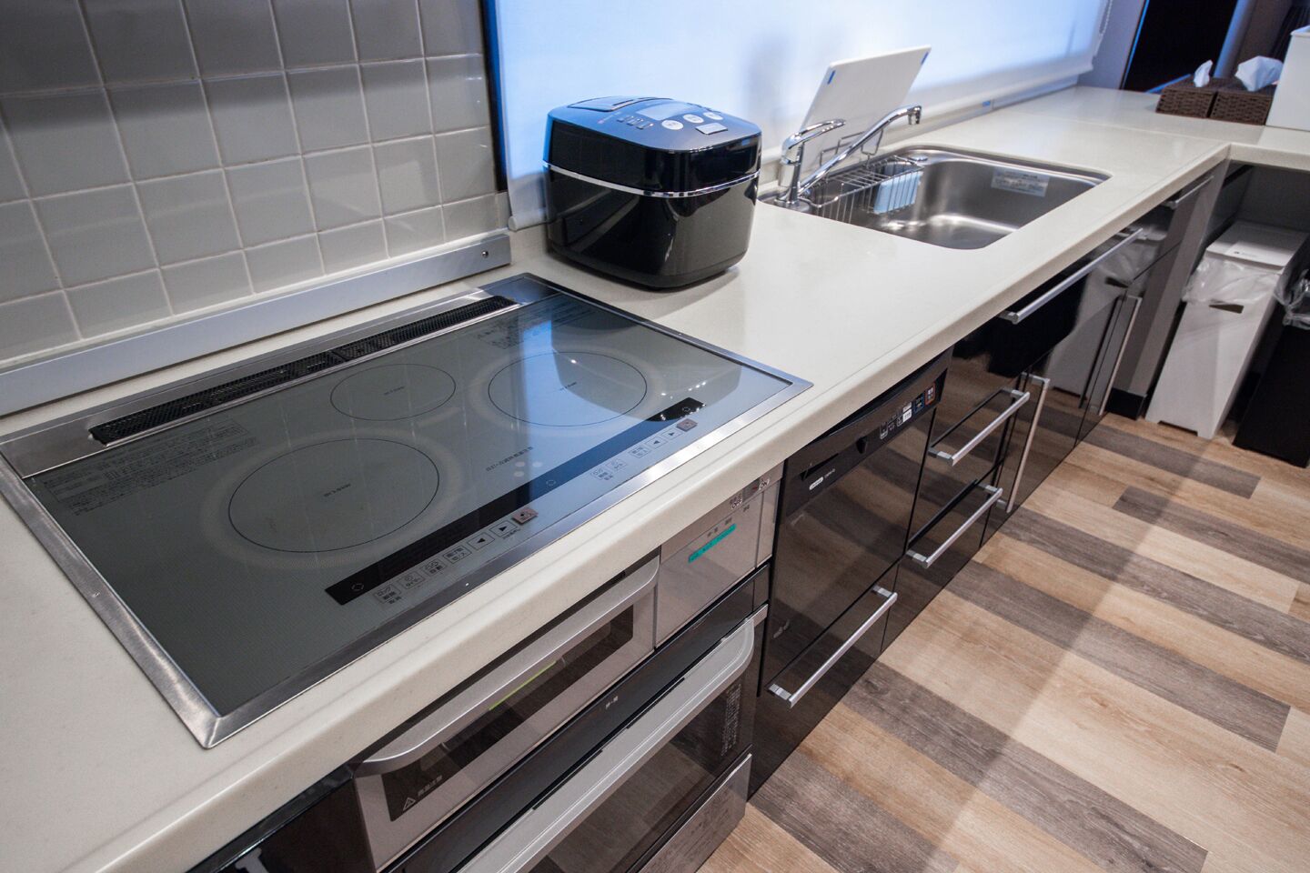 A modern kitchen with a built-in induction cooktop, a dishwasher, and a compact oven.