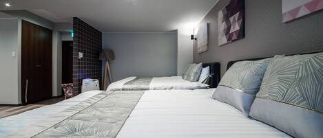 A modern hotel room with two beds, a wardrobe, a desk, and a lamp.