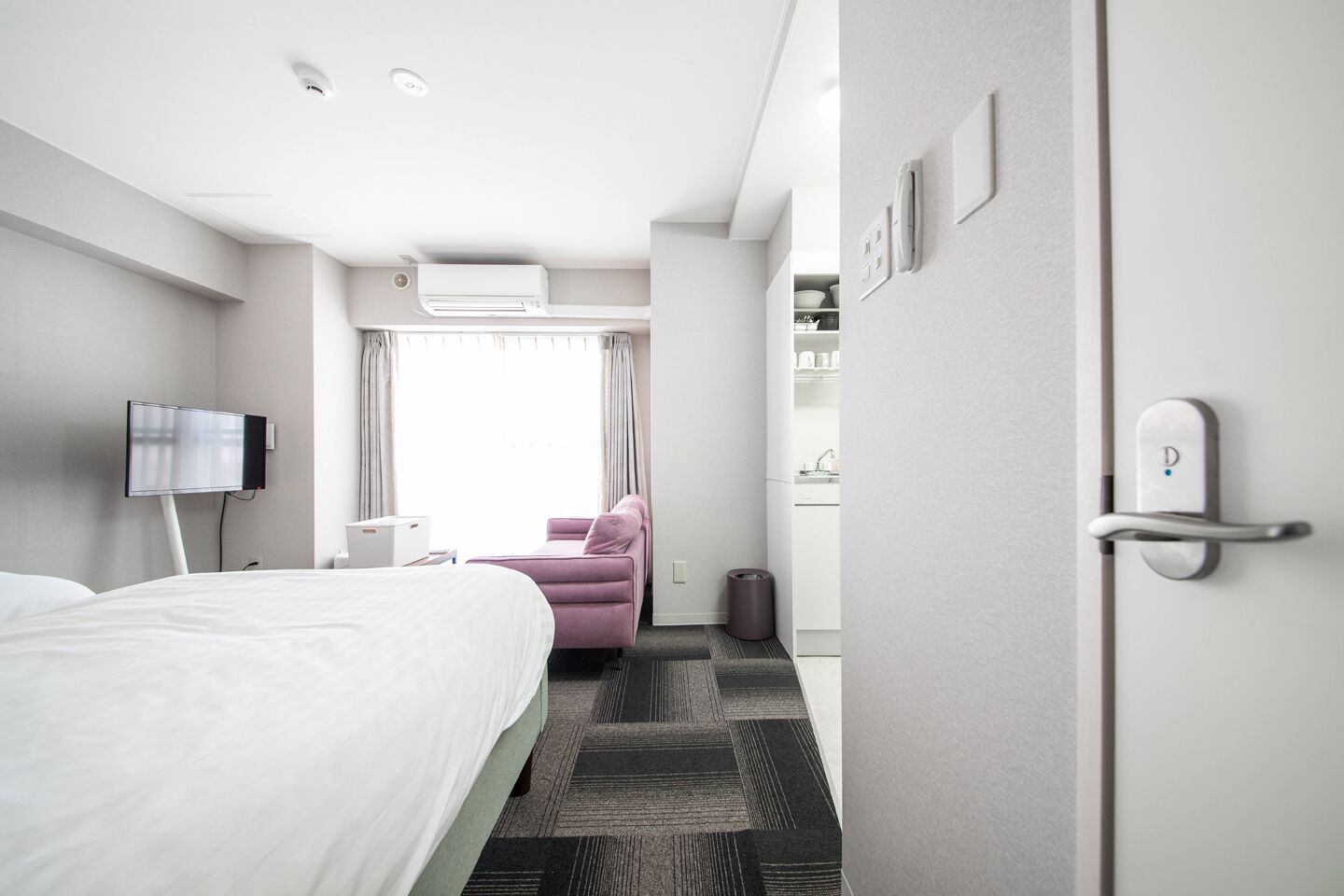 Moderni hotellihuone, jossa on sänky, työpöytä, tuoli, televisio ja kylpyhuone.