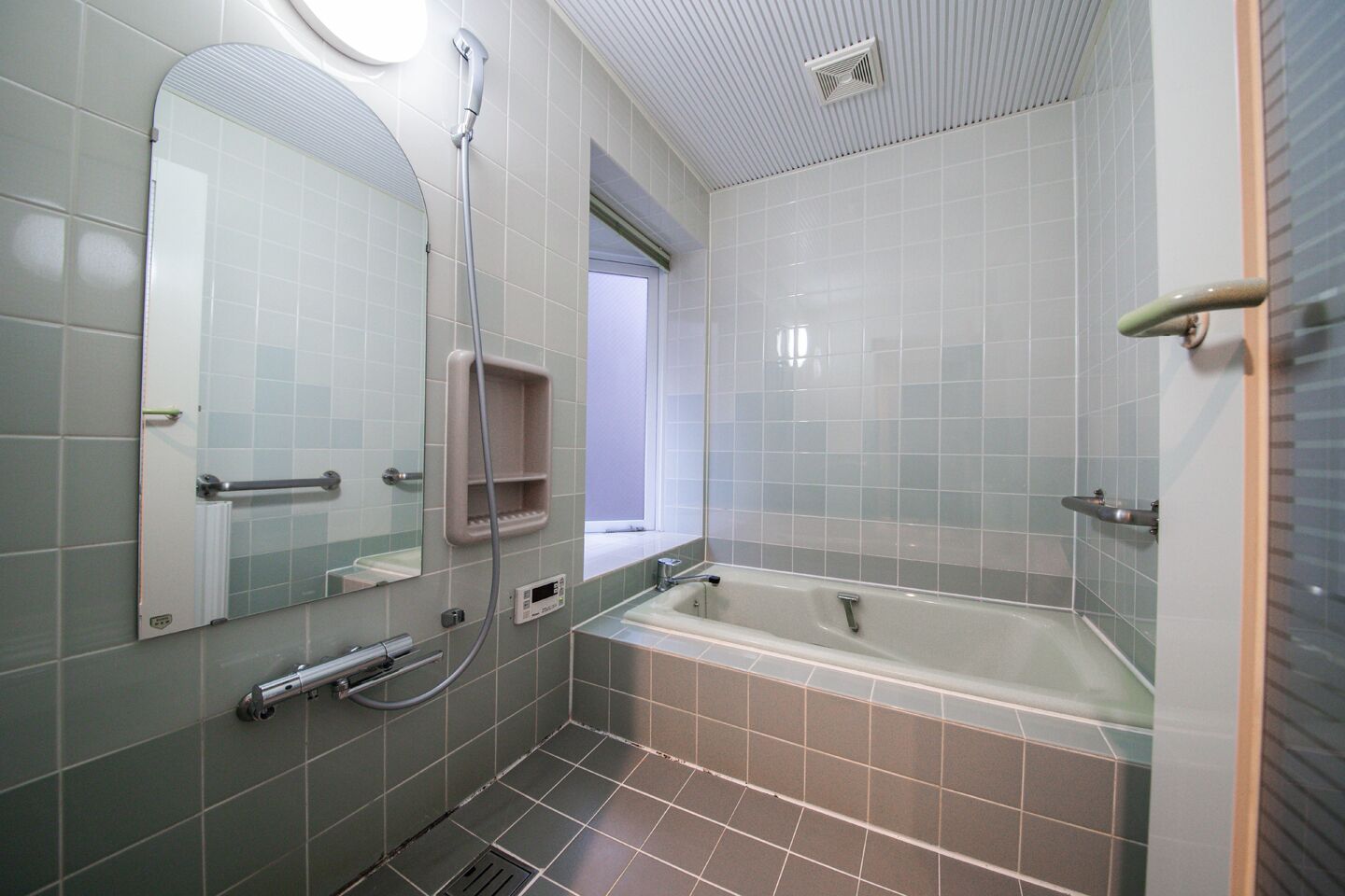 A modern bathroom with a bathtub, a shower, a large mirror, and a window.