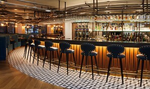 A bar area with stools, a bar counter, and a variety of bottles and glasses. - Hotel Indigo Manchester - Victoria Station by IHG (Manchester)