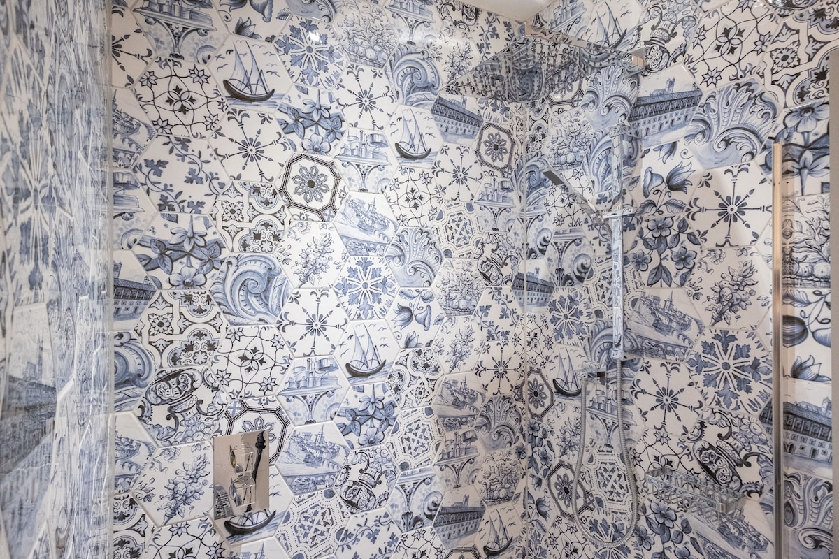 Une pièce dont un mur est recouvert de carreaux bleus et blancs formant un motif.
