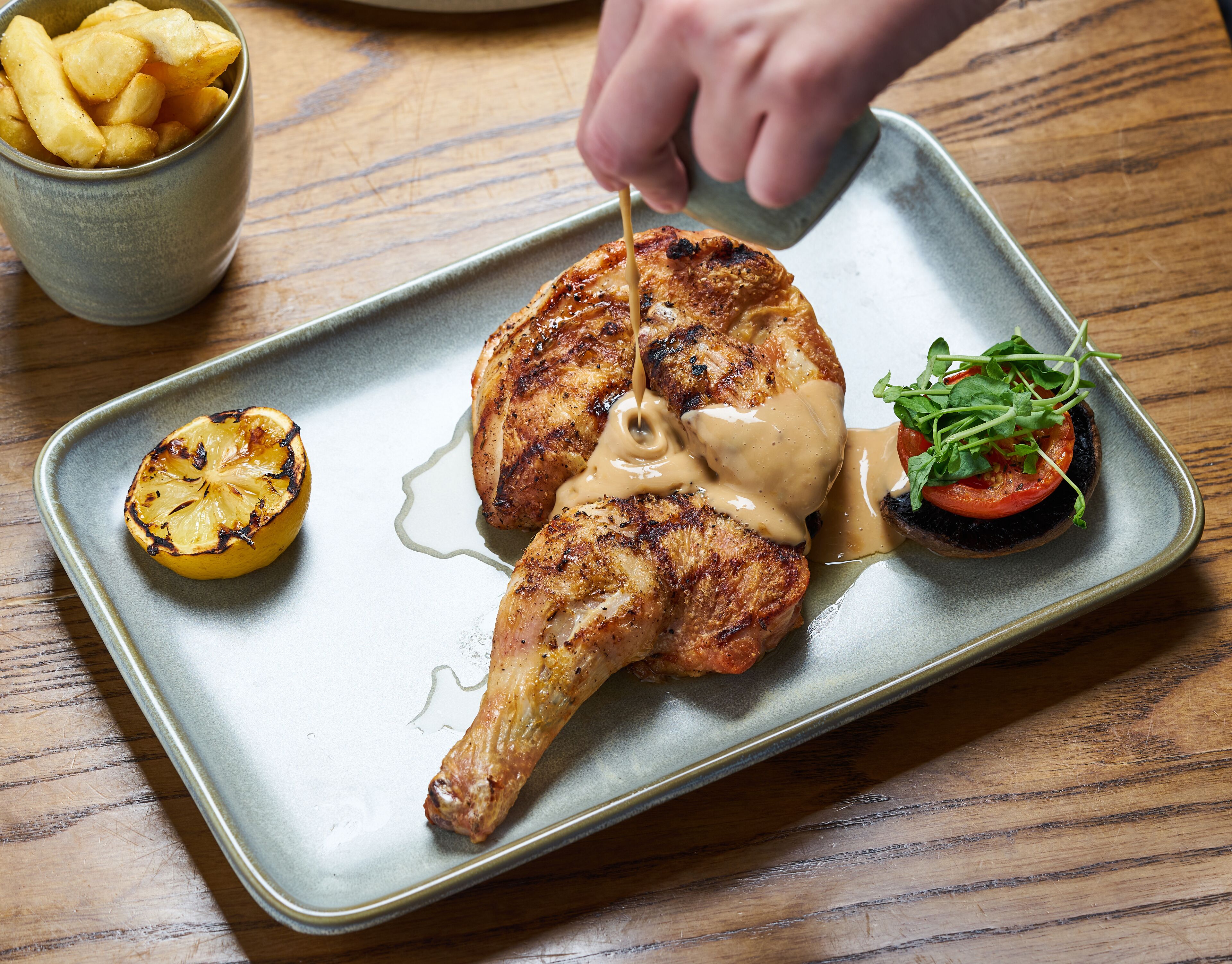 A plate with grilled chicken, a slice of lemon, and a small salad.