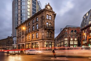 A historic building with a clock tower, large windows, and a street view with moving vehicles. - Hotel Indigo Manchester - Victoria Station by IHG (Manchester)