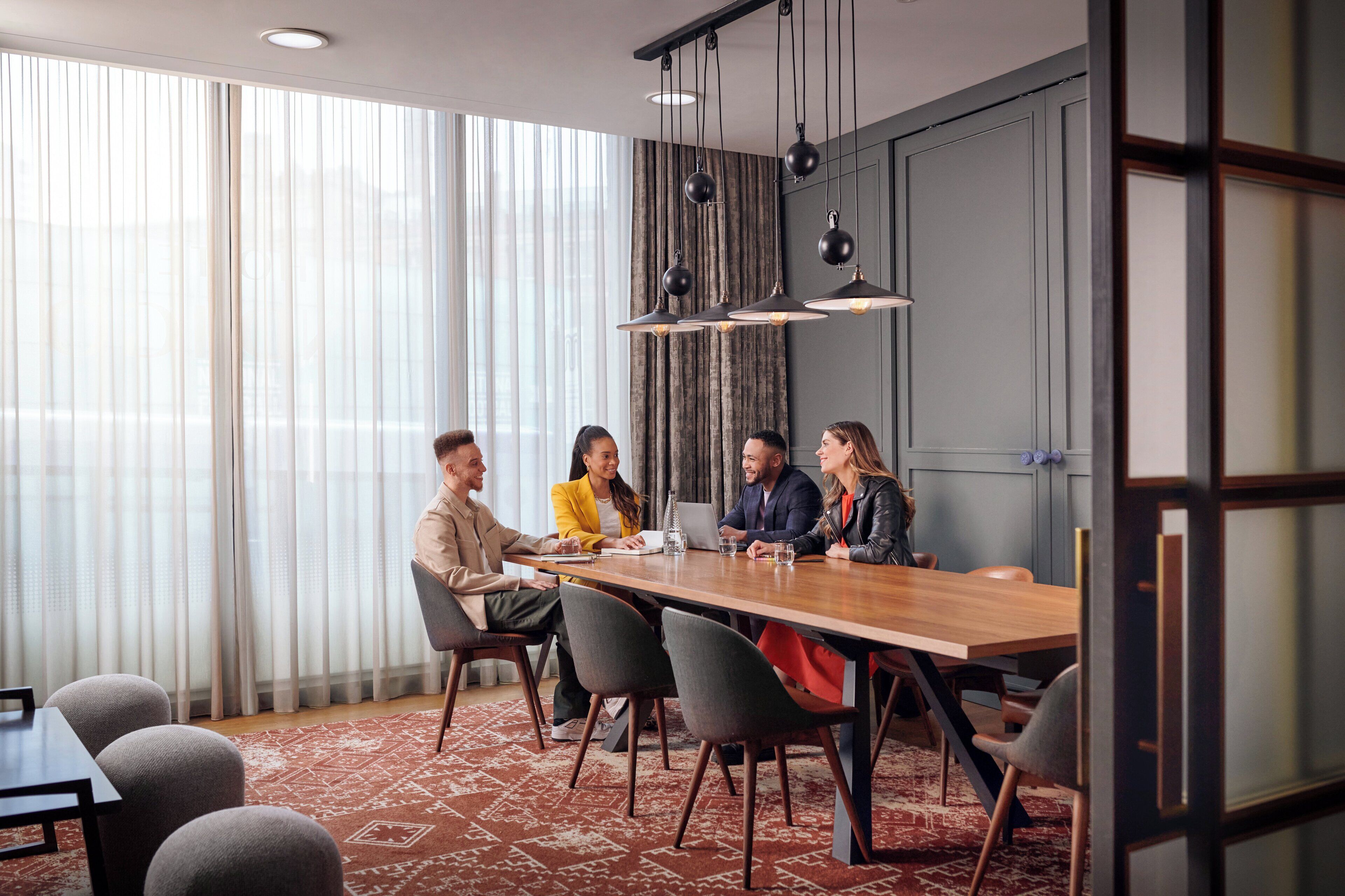 Une salle de conférence avec une longue table, des chaises et des lampes suspendues.