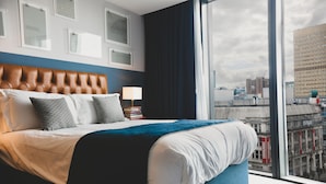 A modern hotel room with a large bed, a view of the city, and a window with curtains. - Hotel Indigo Manchester - Victoria Station by IHG (Manchester)