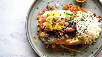 Un plato con un filete de pescado, verduras y queso.