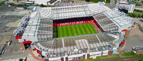 An aerial view of a stadium with a large central field and multiple tiers of seating.