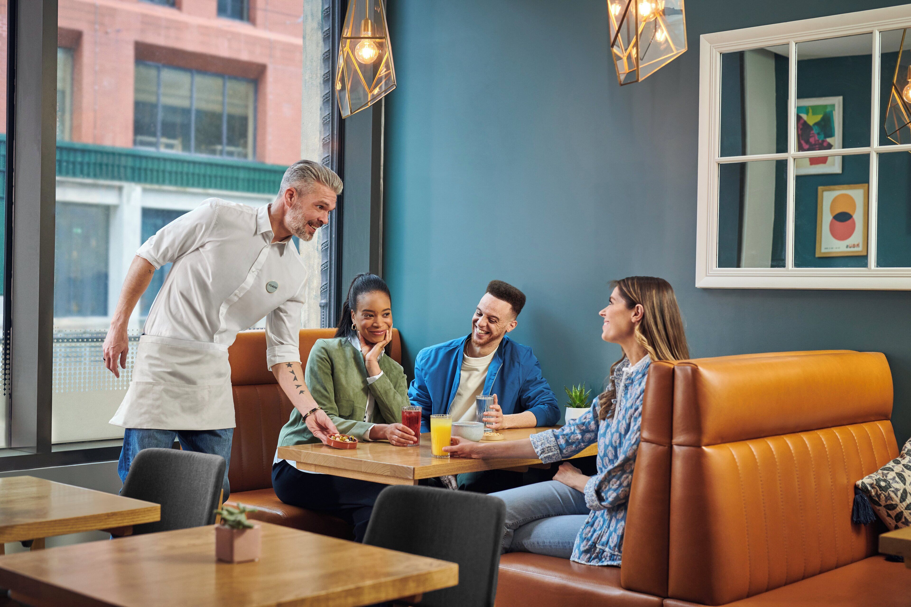 Un grupo de personas sentadas en una mesa en un restaurante con vistas a un edificio.