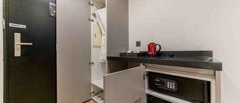 A compact kitchen with a microwave, a coffee maker, and a built-in oven.
