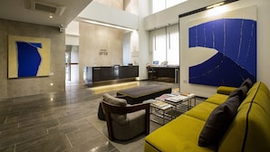 A modern hotel lobby with a reception desk, seating area, and artwork. - Hotel Arte (Suwon)