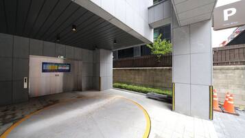 Una entrada de hotel moderna con un camino despejado, un cartel que indica el estacionamiento y un ascensor visible.