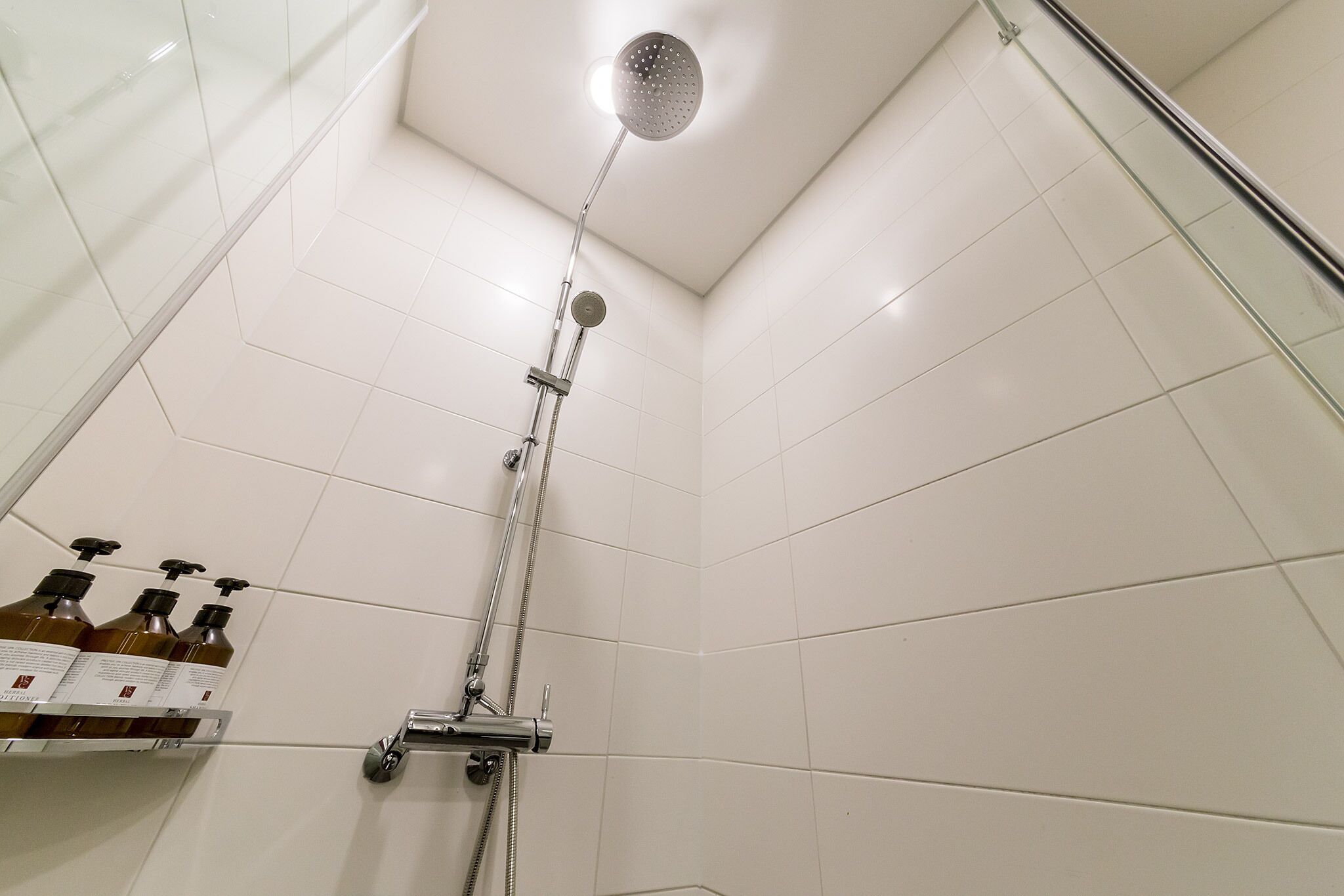 A shower with a handheld showerhead and a wall-mounted faucet.
