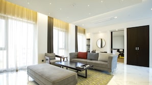 A modern living room with a sofa, ottoman, coffee table, and a large mirror. - Hotel Arte (Suwon)