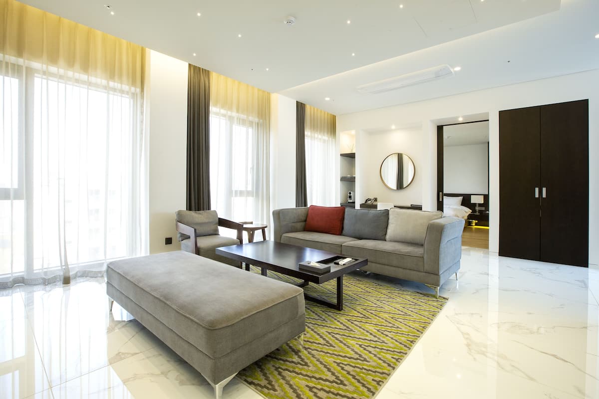 Una sala de estar moderna con sofá, reposapiés, mesa de centro y un espejo grande.