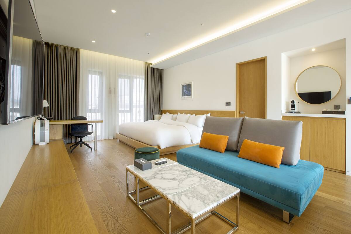 Una habitación de hotel moderna con una cama, un sofá, un escritorio y una televisión.