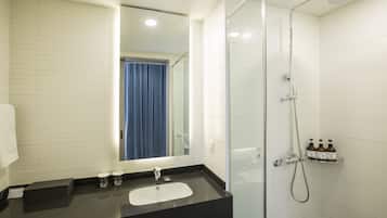A modern bathroom with a glass shower enclosure, a black sink, and a mirror.