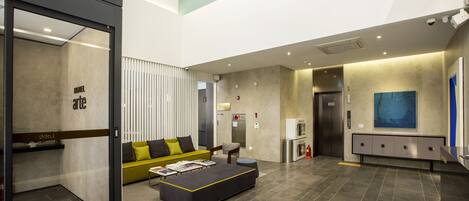 A modern lobby with a sofa, ottoman, and a reception desk.