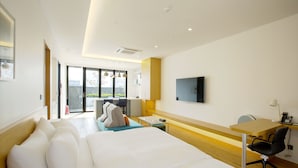 A modern hotel room with a large bed, a desk with a chair, a TV mounted on the wall, and a view of the outdoors through the sliding glass door. - Hotel Arte (Suwon)
