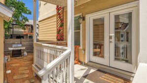 A covered porch with a grill, a white railing, and a door with glass panels. - Walkable South Congress Home + Guest House (Austin)