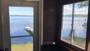 A cabin with a large window overlooking a lake, a dock, and a boat. - Cabin #1 - "Chickagami" (Carp Lake)