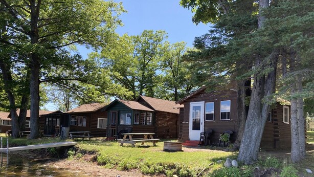 A rustic cabin-style lodging with a small pond, picnic tables, and a wooden deck. - Cabin #1 - "Chickagami" (Carp Lake)