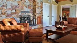 Una chimenea de piedra, sofás de cuero y una mesa de centro de madera en una sala de estar.