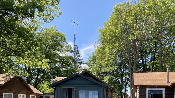 Eine rustikale Holzhütte mit einer Holzterrasse, die zu einem kleinen Steg über dem Wasser führt.