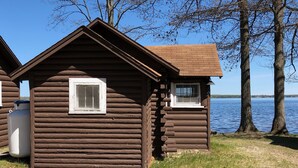 Eine Holzhütte mit kleinem Fenster und Tür, am See gelegen.