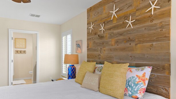 A bedroom with a wooden headboard, a bed with white bedding, and decorative pillows.