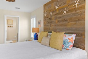 Een slaapkamer met een houten hoofdeinde, een bed met wit beddengoed en decoratieve kussens.
