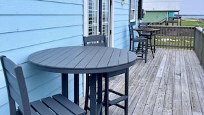 A blue house with a deck, a table, and chairs.