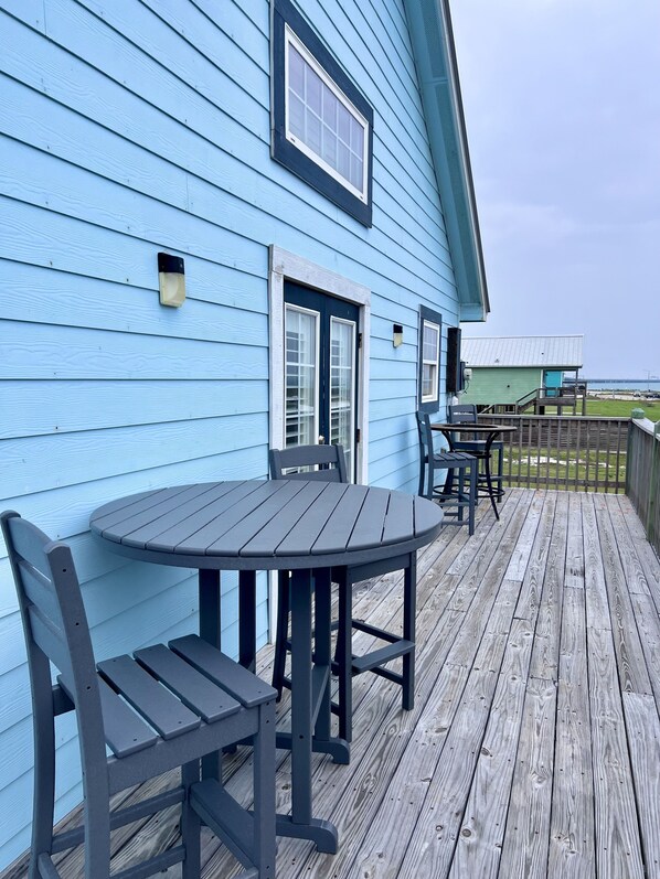 A blue house with a deck, a table, and chairs.