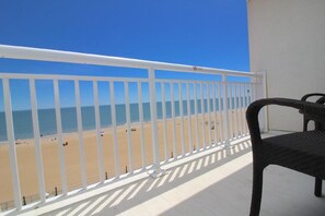Un balcón con barandilla blanca que da a una playa.