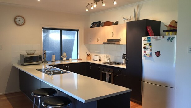 A modern kitchen with a central island, black cabinets, a refrigerator, and a clock on the wall. - Free WIFI **200m to beach** R/C Air in all rooms  (Moonta Bay)