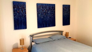A bedroom with a bed, two bedside tables, and three abstract paintings on the wall. - Free WIFI **200m to beach** R/C Air in all rooms  (Moonta Bay)