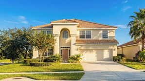 A two-story house with a tiled roof, a front garage, and a well-maintained lawn.