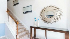 A staircase with wooden railings and a dark wooden console table with two white candle holders.