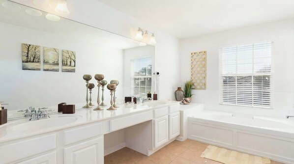 Un baño moderno con un espejo grande, muebles blancos, un lavamanos doble e una bañera independiente.