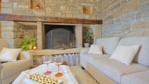 A cozy living room with a stone fireplace, two sofas, a coffee table with snacks and wine glasses, and a potted plant. - Villa Alba with breathtaking view from swiming pool, HEATED POOL, near Motovun (Livade)