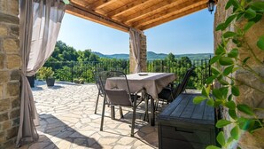 A covered patio with stone flooring, a table and chairs, and a view of greenery and hills. - Villa Alba with breathtaking view from swiming pool, HEATED POOL, near Motovun (Livade)