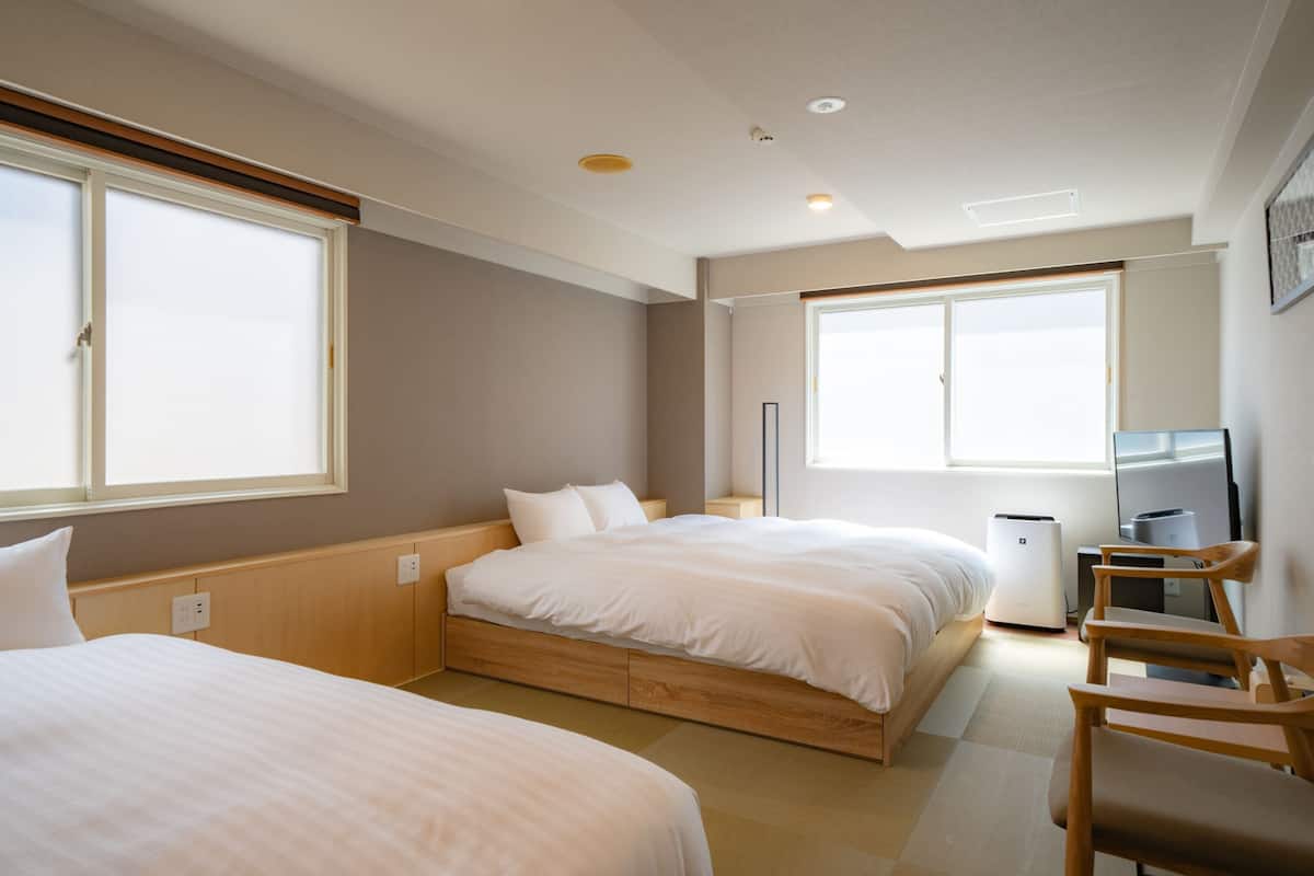 A hotel room with two beds, a desk, and a chair.