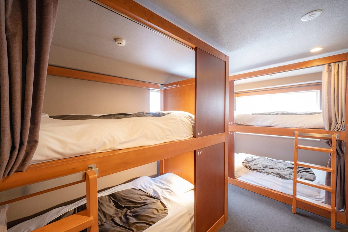A bunk bed room with wooden frames and curtains.