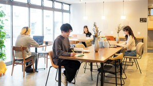 A modern conference room with large windows, wooden furniture, and a central table with laptops and a vase. - GRAND HOSTEL LDK ODORI PARK (Sapporo)