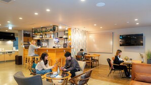 A modern lounge area with seating arrangements, a bar area, and a television screen. - GRAND HOSTEL LDK ODORI PARK (Sapporo)