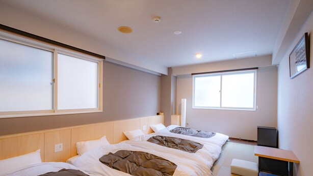 A modern hotel room with two beds, a small desk, and large windows providing natural light. - GRAND HOSTEL LDK ODORI PARK (Sapporo)