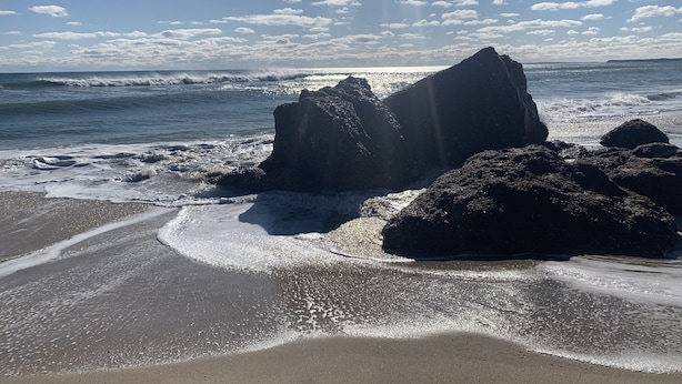 Ein Strand mit großen Felsen und Wellen.