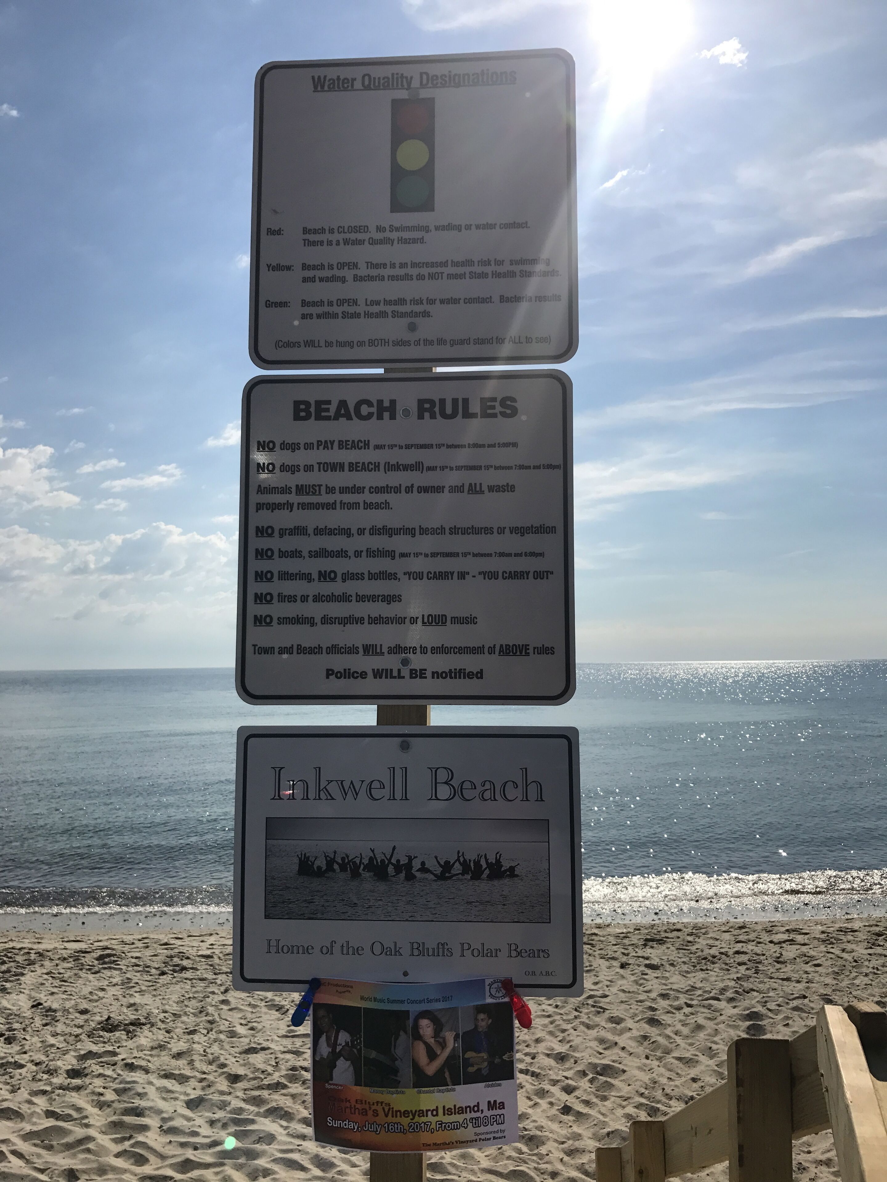 En skilte ved stranden med information om vandkvalitet og regler.