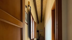 Un couloir avec des lambris en bois, un plafond en pente et un revêtement de sol carrelé.